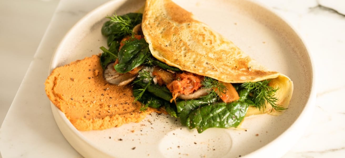 A cooked omelette on a plate with vegetables